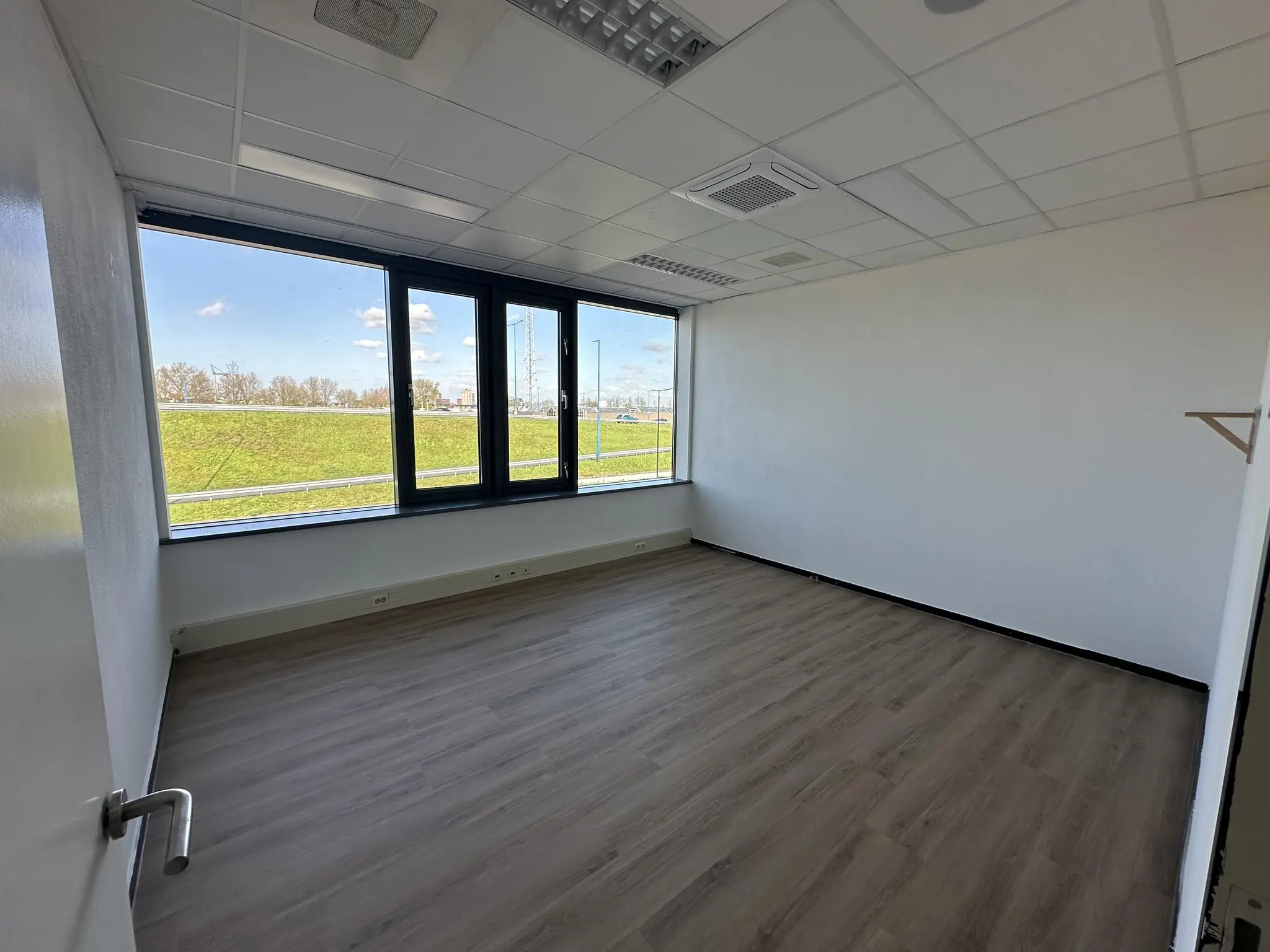 Leeg, licht kantoor aan de Van der Hagenstraat met uitzicht op een groene dijk.